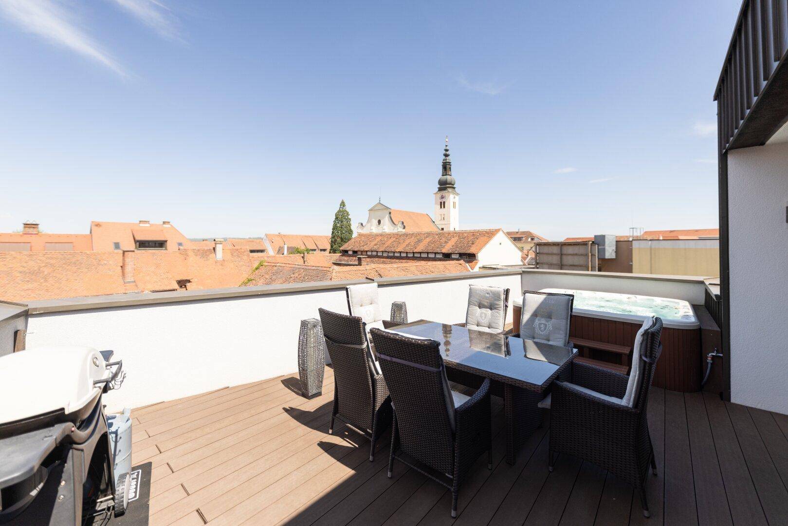 Geräumige Dachterrasse mit Essbereich, Whirlpool und weitem Blick über die Dächer der Stadt.