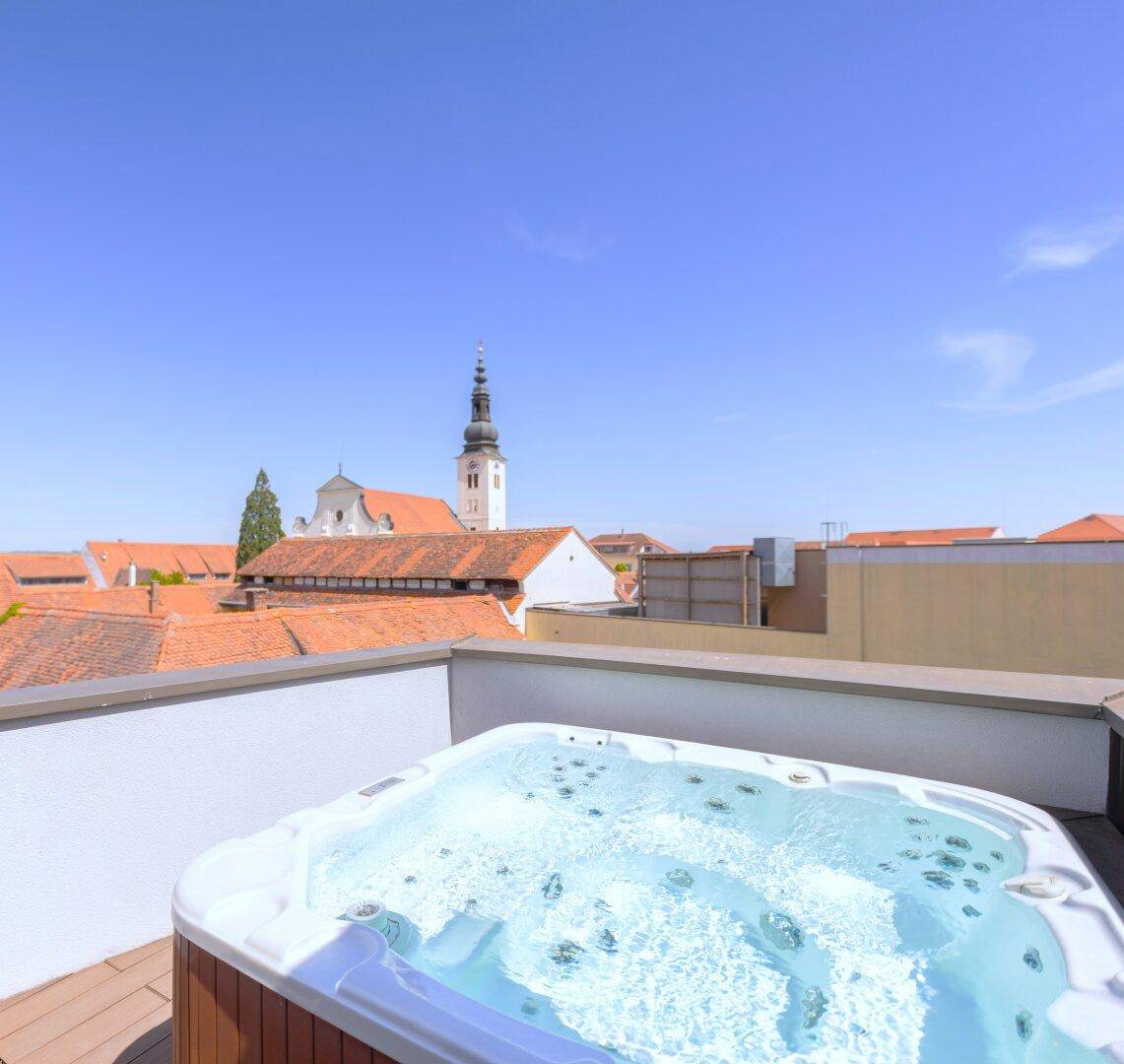 Entspannender Whirlpool auf der Dachterrasse mit Panoramablick über die historischen Dächer der Stadt.