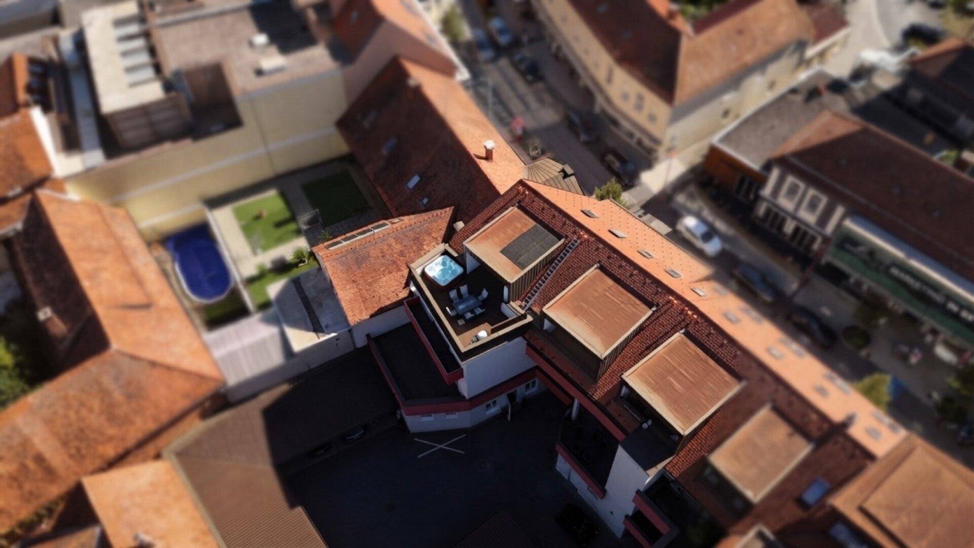Luftaufnahme eines Gebäudekomplexes mit Dachterrasse und integriertem Whirlpool.