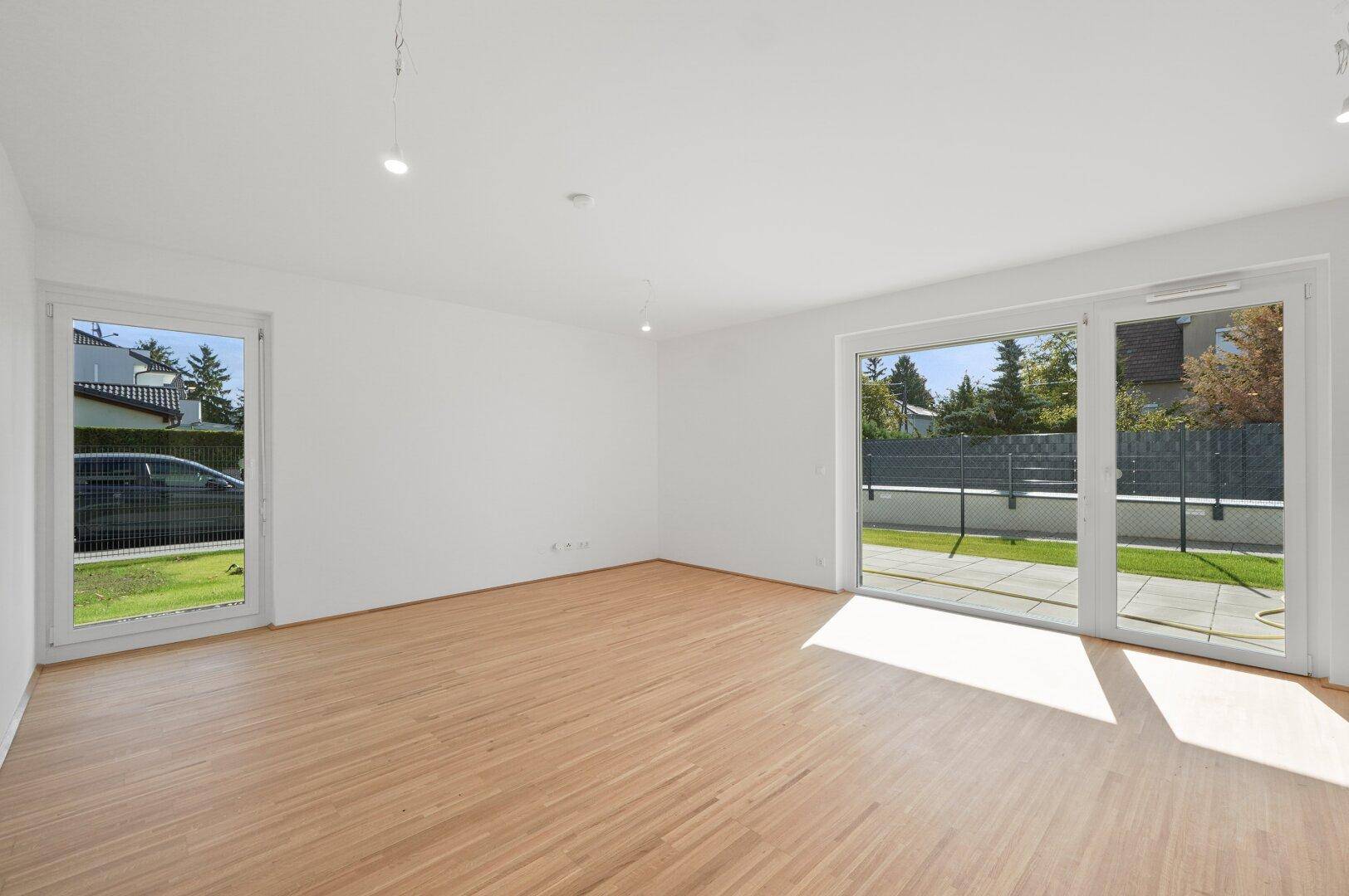 Geräumiges Wohnzimmer mit Holzfußboden und großen Schiebetüren, die direkten Zugang zum Garten ermöglichen.