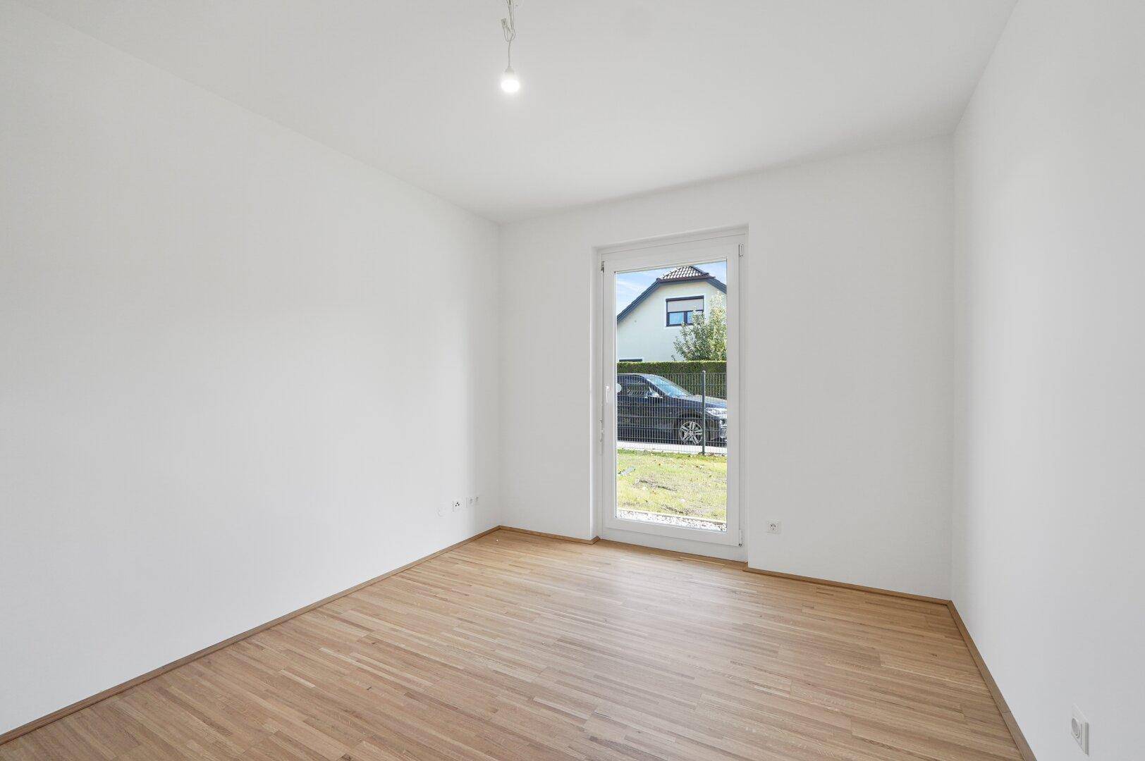 Helles Zimmer mit Holzfußboden und einer Tür, die den Zugang zum Außenbereich ermöglicht.