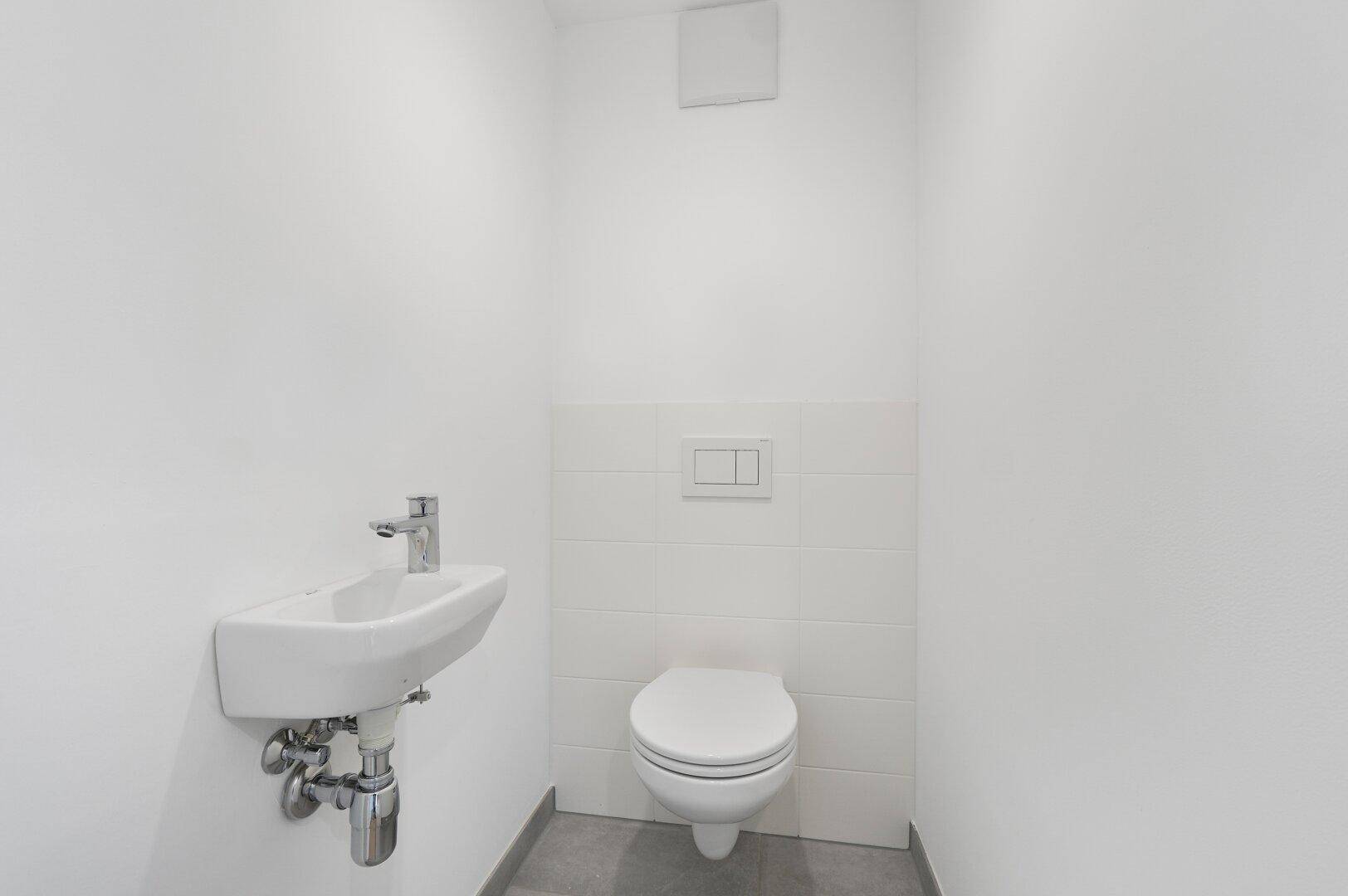 Kleines, helles Gäste-WC mit wandhängender Toilette und kompaktem Waschbecken.