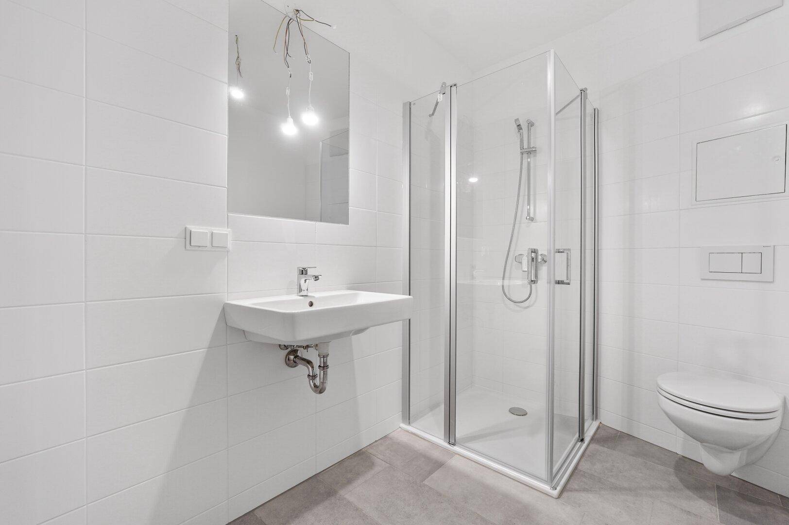 Modernes Badezimmer mit weißen Fliesen, Glasdusche, wandhängendem WC und einem einzelnen Waschbecken.