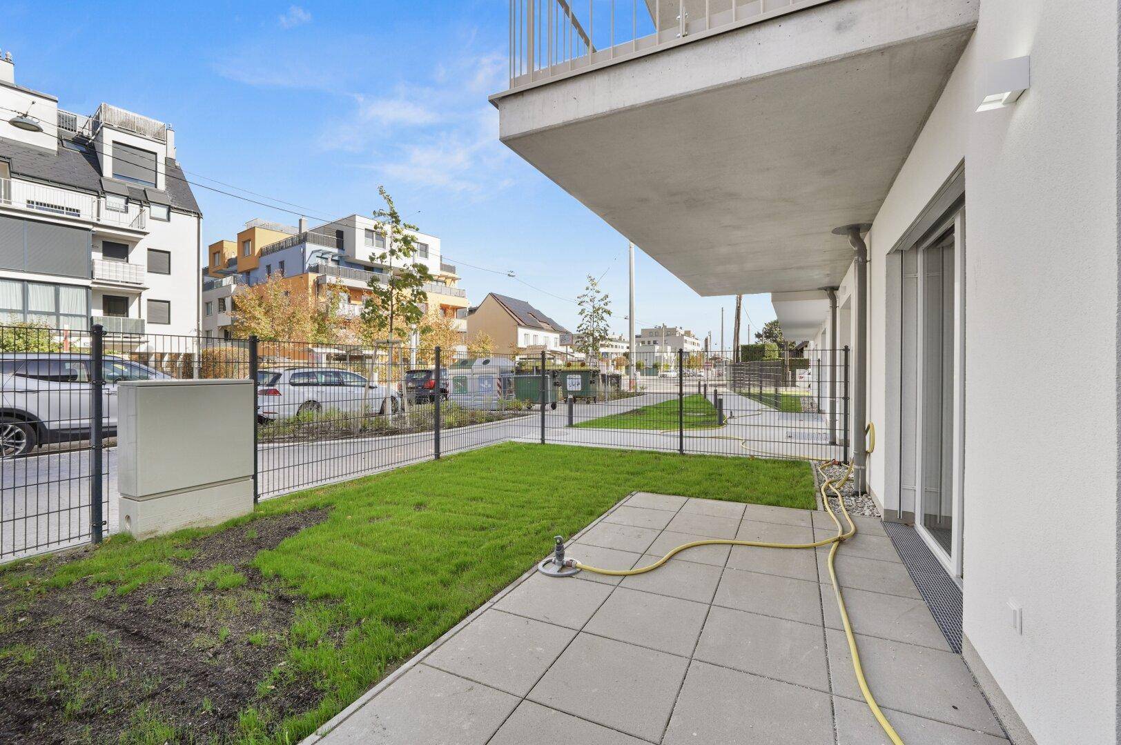 Kleine gepflasterte Terrasse mit Rasenfläche und direktem Zugang zum Gartenbereich des Gebäudes.