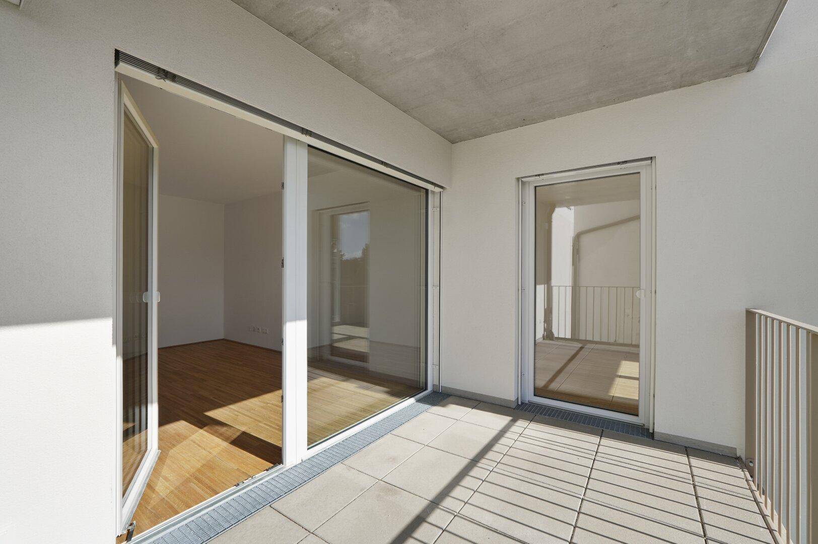 Heller Balkon mit Fliesenboden und großen Glasfronten, die den Innenraum mit Licht durchfluten.