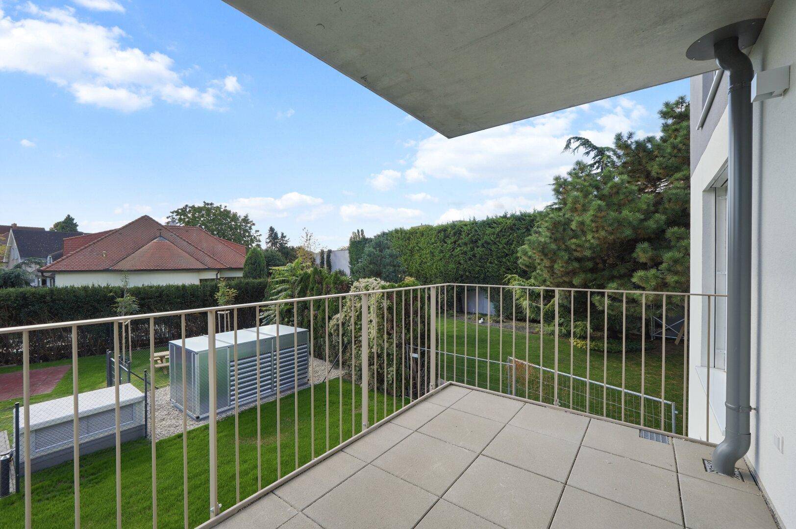 Balkon mit Blick auf den grünen Garten und die umliegende Wohngegend.