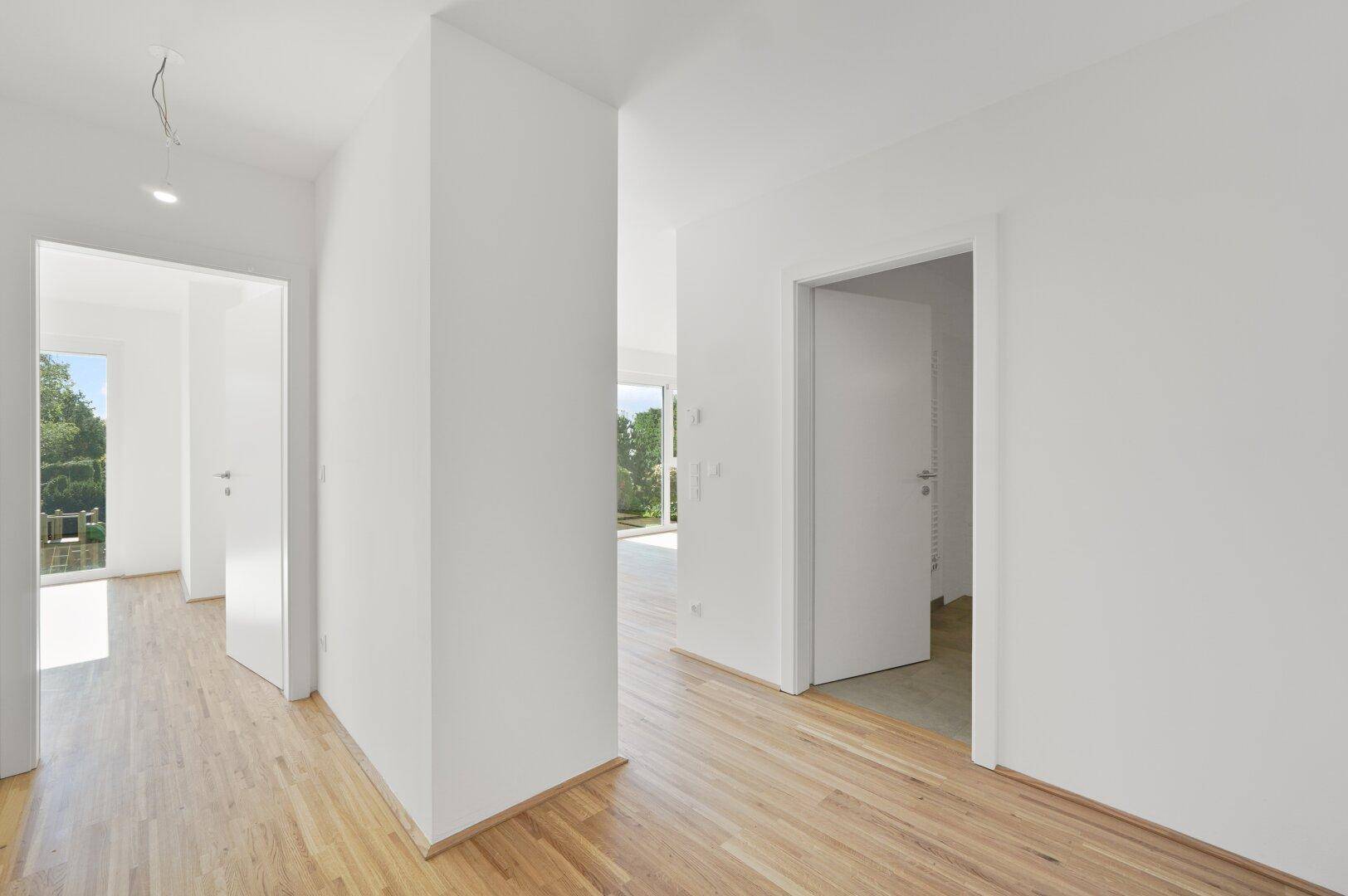 Heller Flur mit Holzboden und Zugang zu verschiedenen Zimmern der Wohnung.