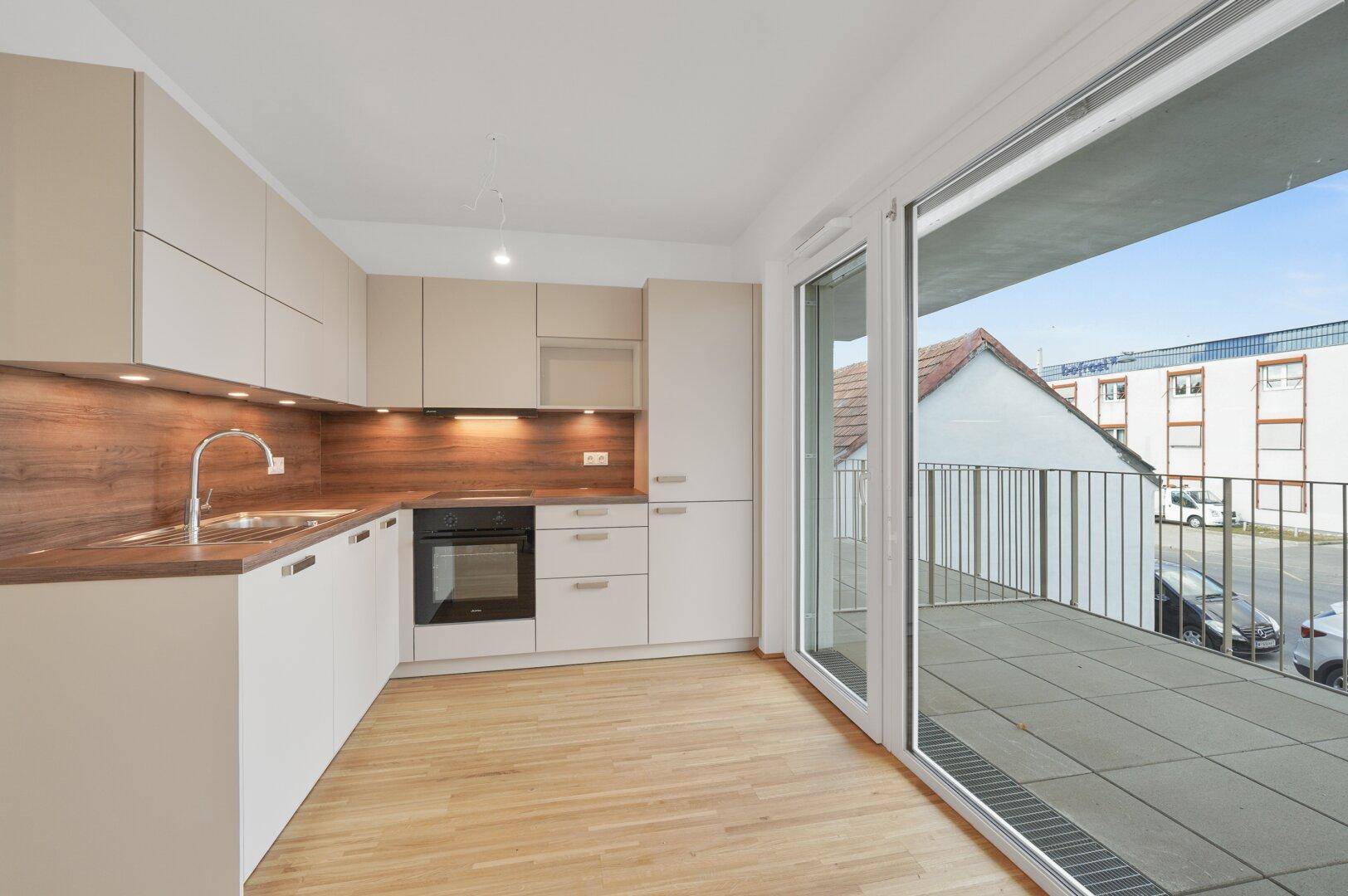 Moderne Einbauküche mit Holzoptik-Arbeitsplatte und direktem Zugang zum Außenbereich.