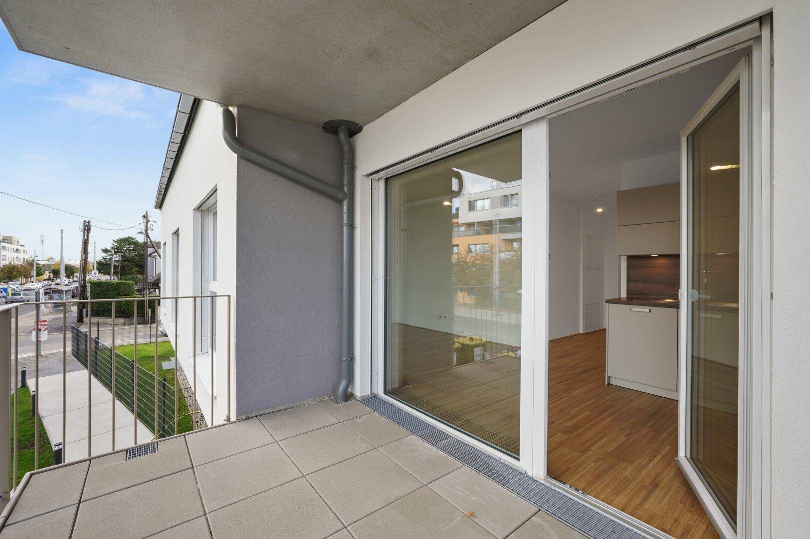 Geräumiger Balkon mit Fliesenboden und Blick auf die umliegenden Gebäude und die Straße.