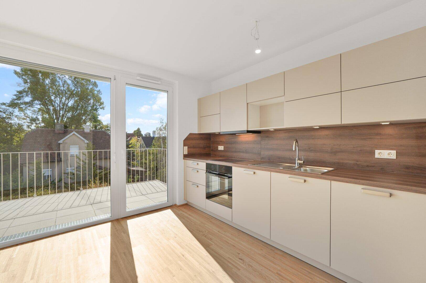 Funktionale Einbauküche mit hellen Fronten, Holzarbeitsplatte und direktem Zugang zum Balkon.