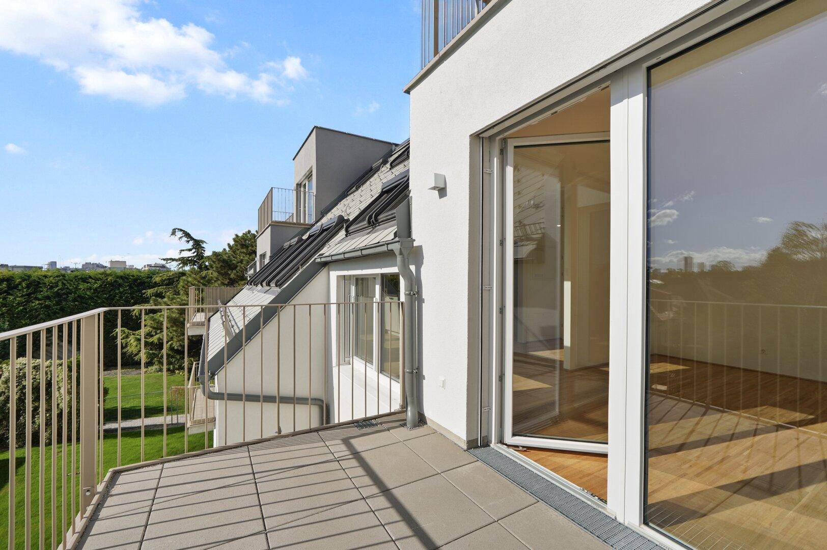Großer Balkon mit Fliesenboden und Blick auf die Umgebung, ideal zum Entspannen im Freien.