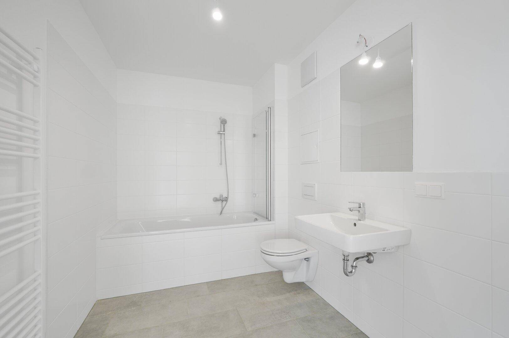 Modernes Badezimmer mit weißen Fliesen, Badewanne und wandmontiertem WC.