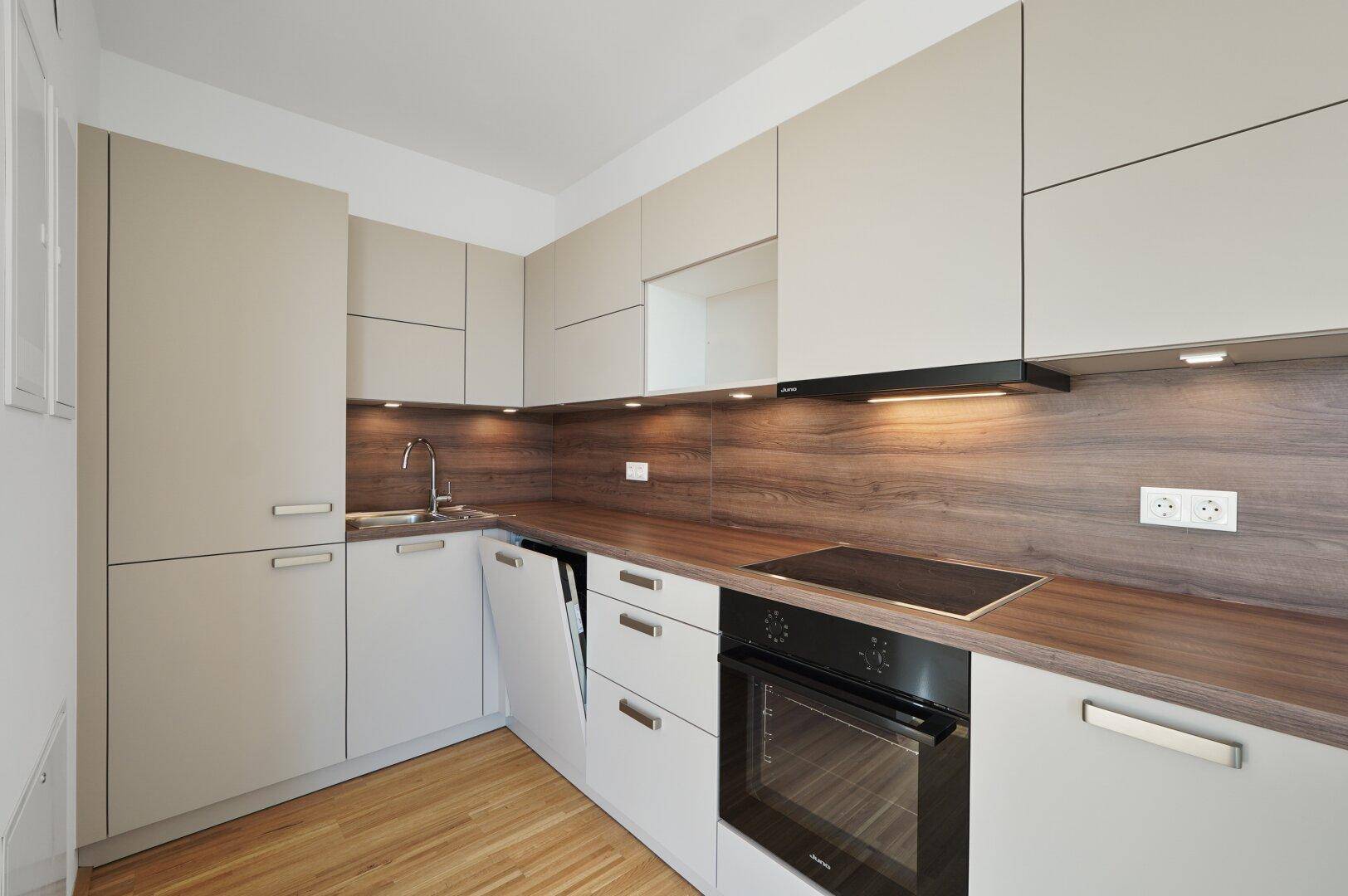Moderne Einbauküche mit hellen Schränken, Holzoptik-Arbeitsplatte und integrierten Geräten.
