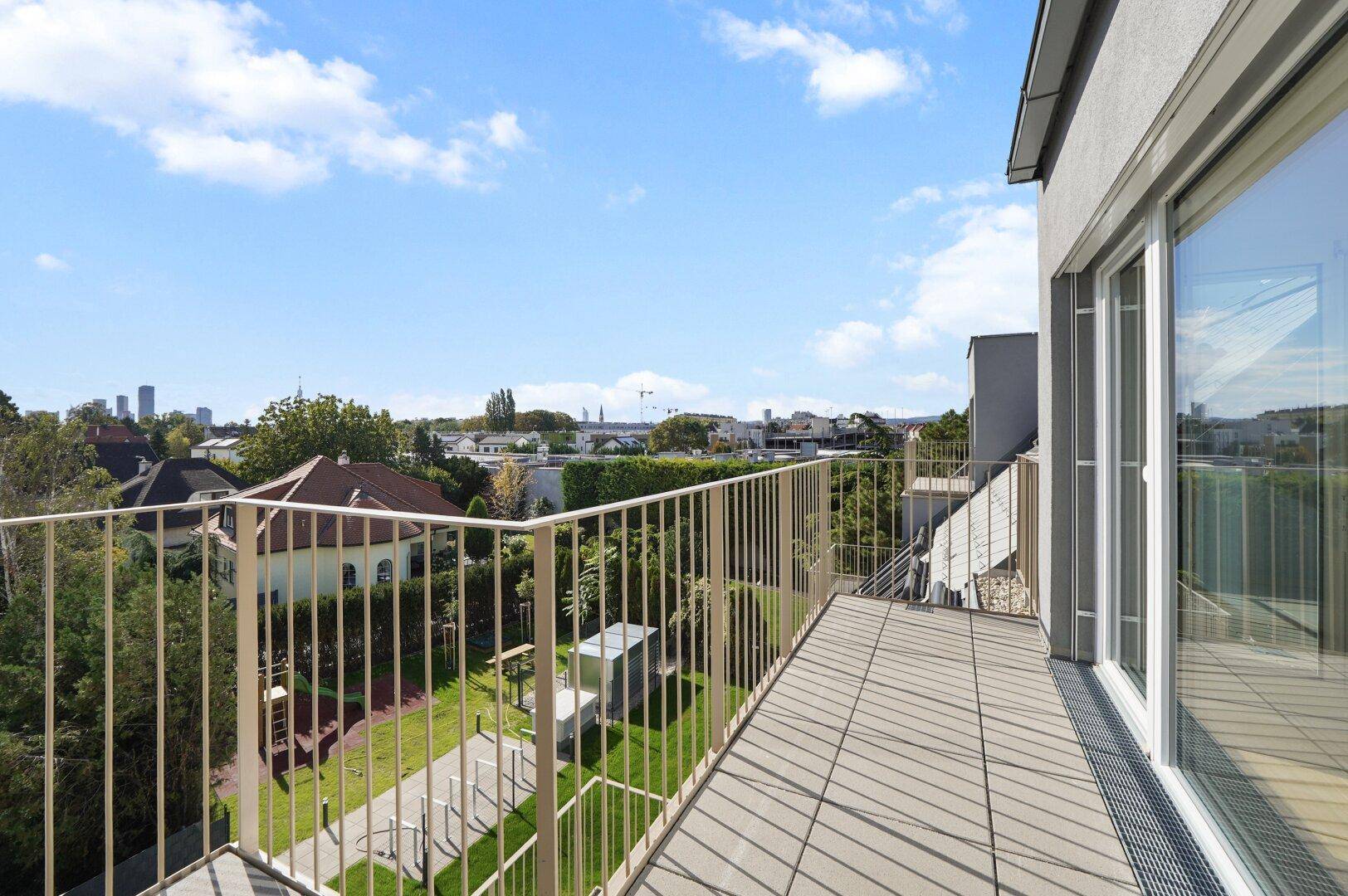 Großer Balkon mit weitem Blick über grüne Gärten und die umliegende Wohngegend.