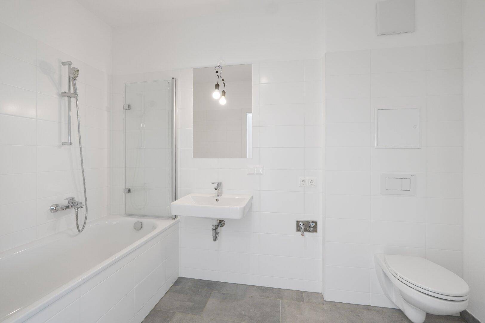 Modernes Badezimmer mit weißen Fliesen, Badewanne mit Duschfunktion und wandhängendem WC.