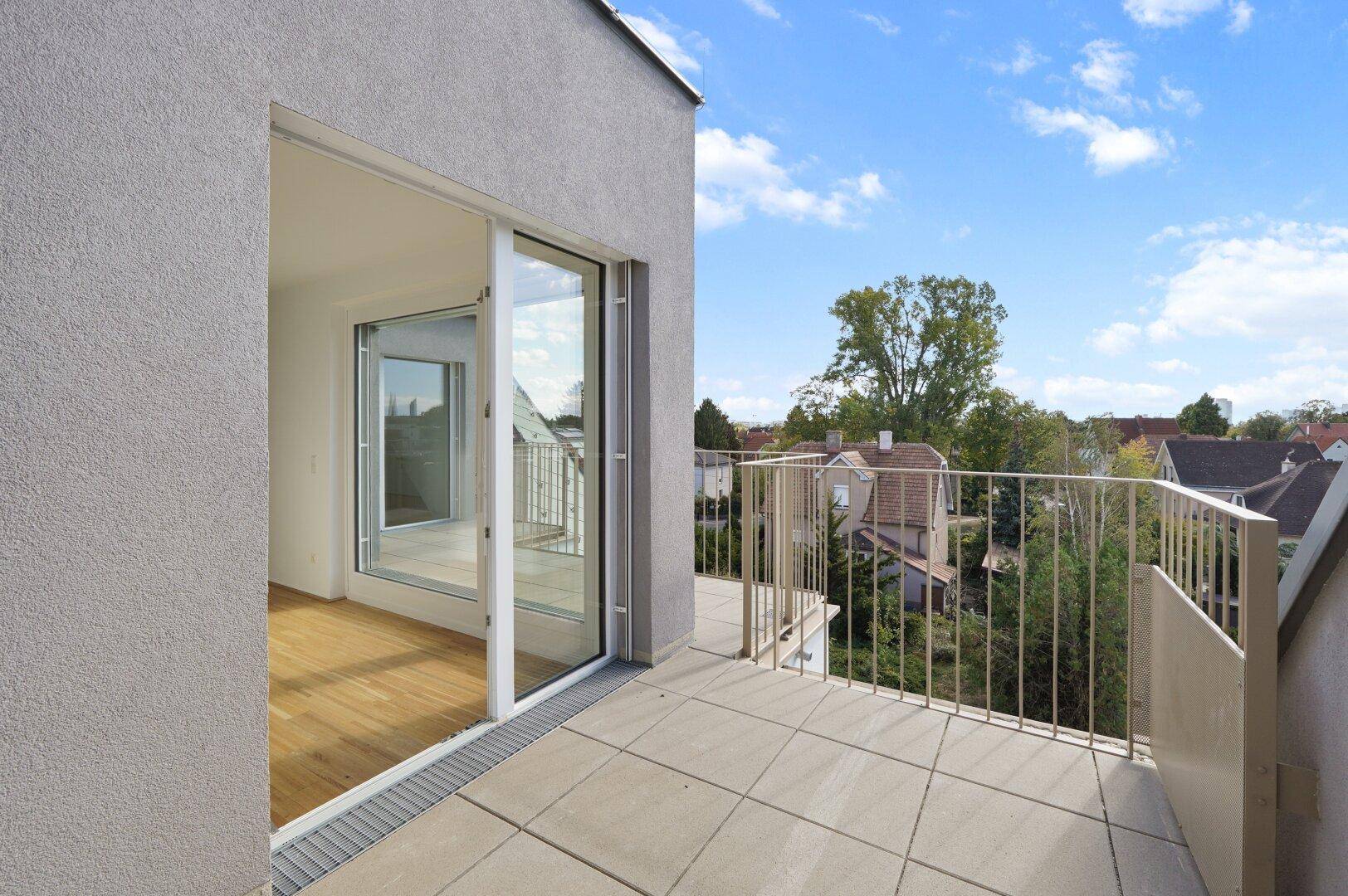 Balkon mit Fliesenboden und Blick auf die umliegenden Häuser und Bäume in der Nachbarschaft.