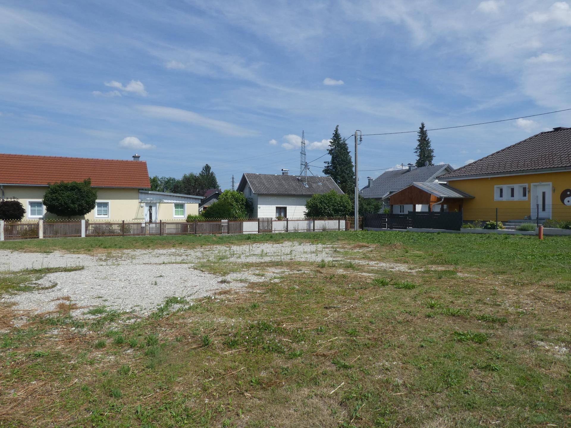 Blick auf eine ländliche Wohngegend mit Einfamilienhäusern und einer ungenutzten Fläche im Vordergrund.