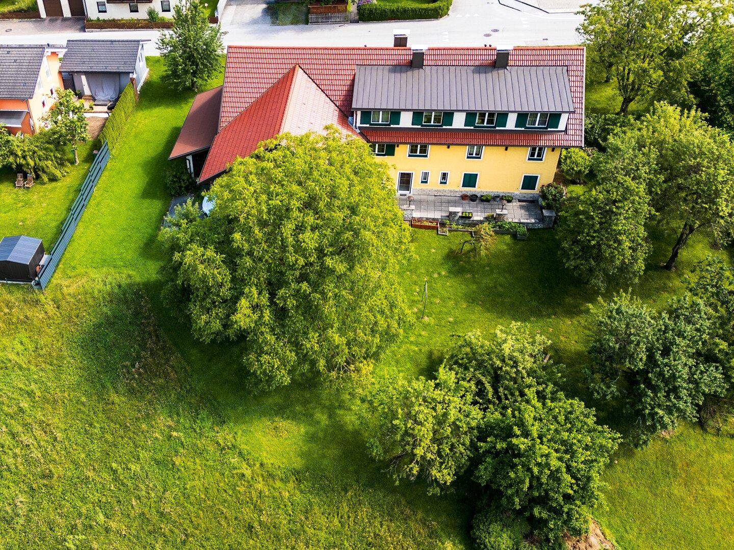 Weitläufige Luftaufnahme des Anwesens mit großem Garten, umgeben von weiteren Häusern und Natur.