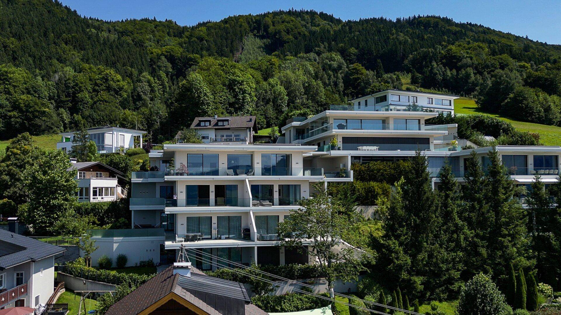 Moderne Architektur von Terrassenhäusern, die sich harmonisch in die bewaldete Hanglage einfügen.