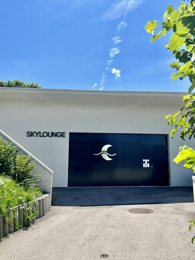 Moderner Eingangsbereich eines Gebäudes mit der Aufschrift "SKYLOUNGE" und einem großen schwarzen Tor.