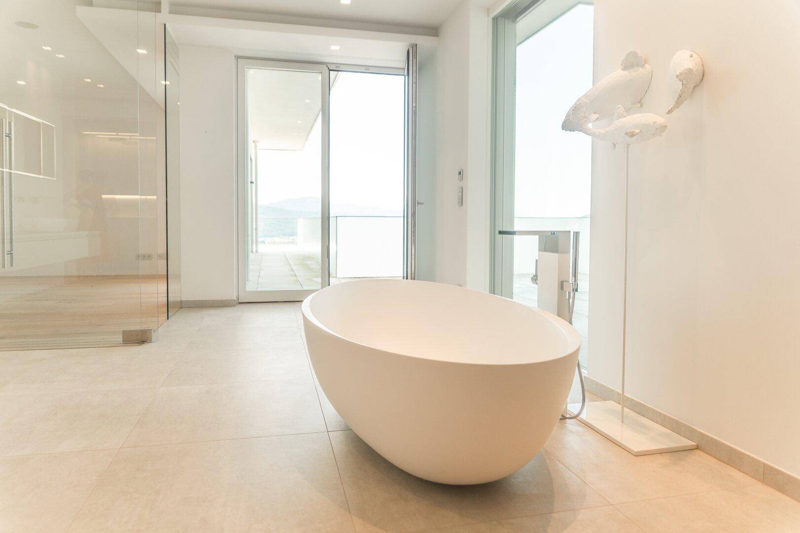 Geräumiges Badezimmer mit freistehender Badewanne und Zugang zu einer Außenterrasse.