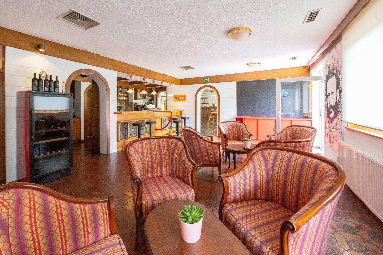 Geräumiger Loungebereich mit Bar, bequemen Sesseln und Terrakotta-Fliesenboden, ideal zum Entspannen.