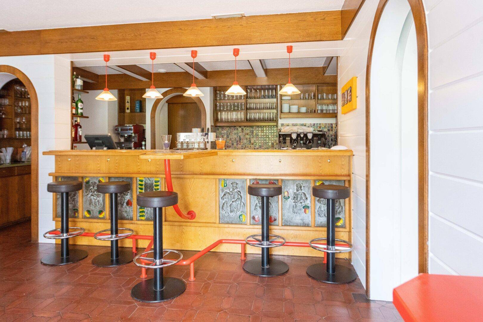 Rustikale Bar mit Holzelementen, Barhockern und einer Auswahl an Getränken in Regalen.