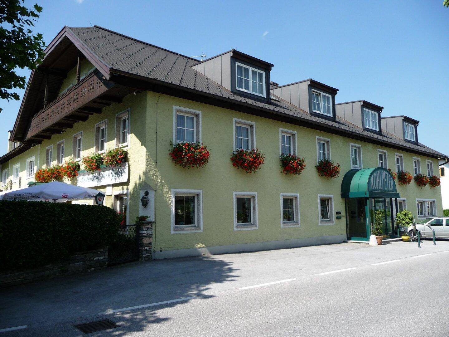 Gesamtansicht des traditionellen Gebäudes mit gelber Fassade, vielen Fenstern und Blumenkästen.