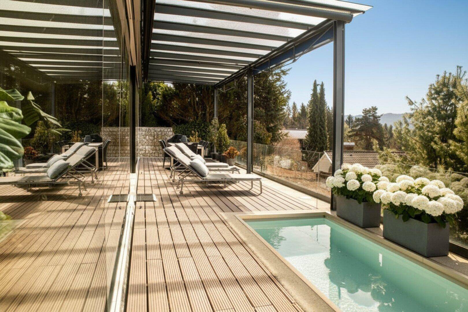 Geräumige Holzterrasse mit kleinem Pool und Liegestühlen, ideal zum Entspannen im Freien.