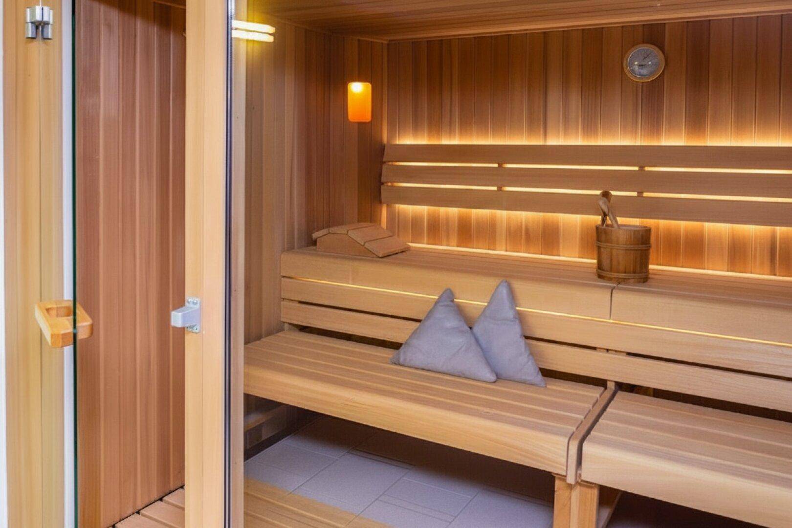 Moderne Holzsauna mit bequemen Bänken und stimmungsvoller Beleuchtung für Entspannung.