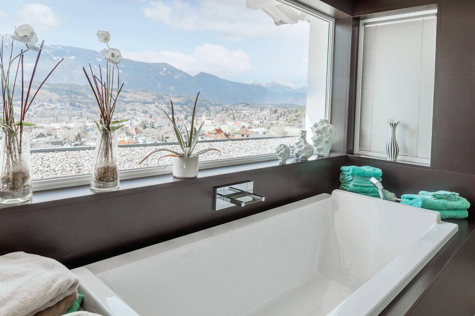 Elegantes Badezimmer mit Badewanne und Panoramablick auf die Stadt und die Berge.