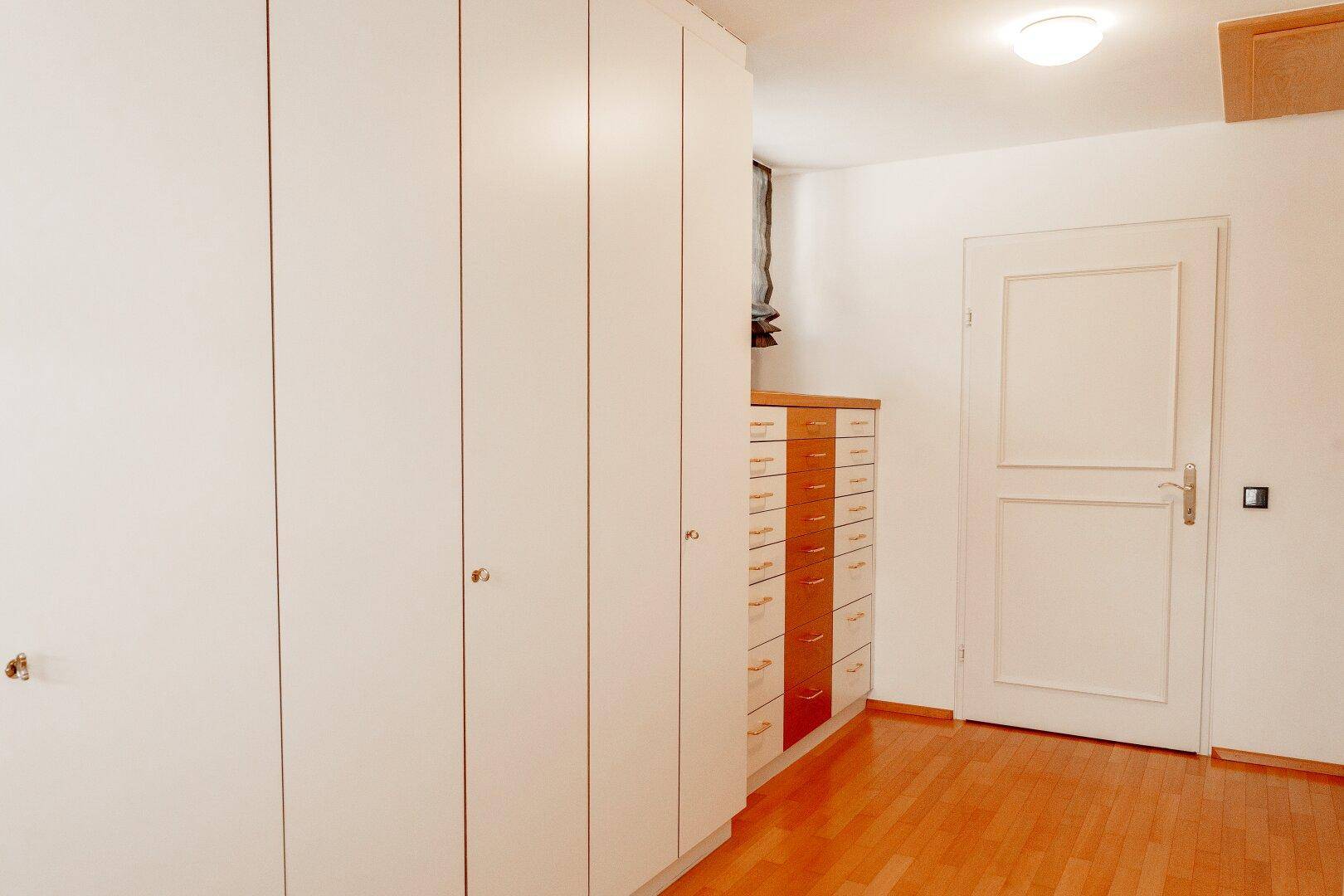 Raum mit praktischen Einbauschränken und Holzfußboden für zusätzlichen Stauraum.