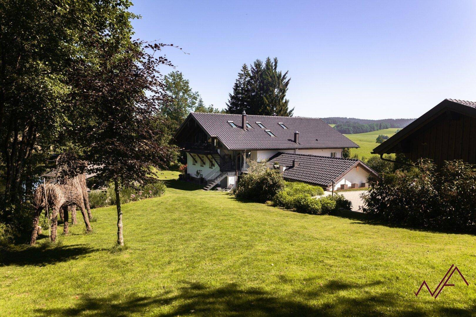 Das Anwesen präsentiert sich mit einem weitläufigen Rasen und einem traditionellen Haus unter blauem Himmel.
