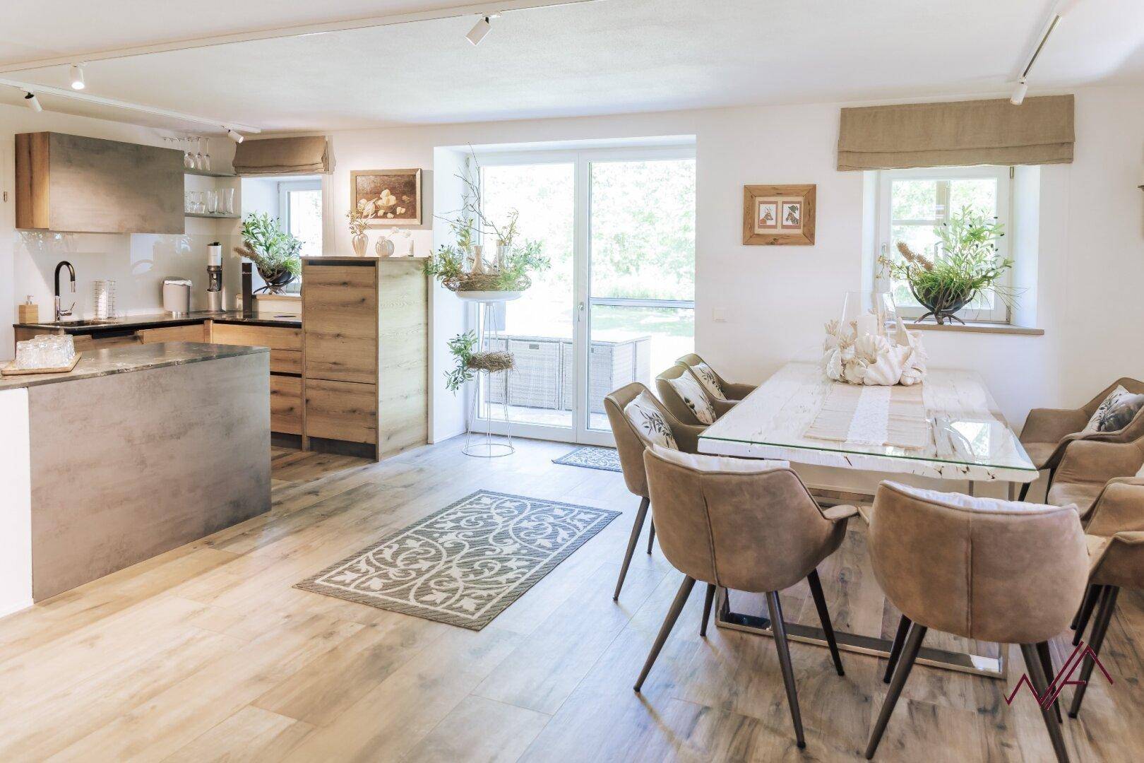 Offene Küche mit Essbereich, modernen Holz- und Betonelementen und Zugang zur Terrasse.