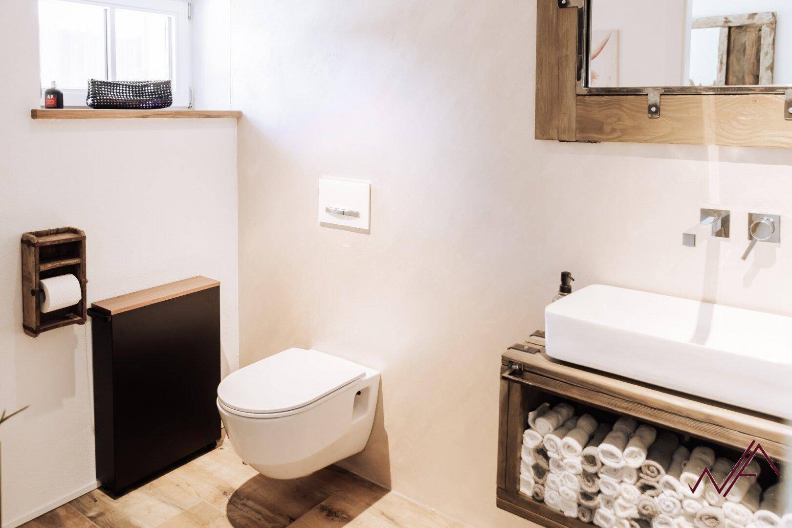 Modernes WC mit Holzwaschtisch, wandhängendem WC und Fenster für natürliche Belüftung.