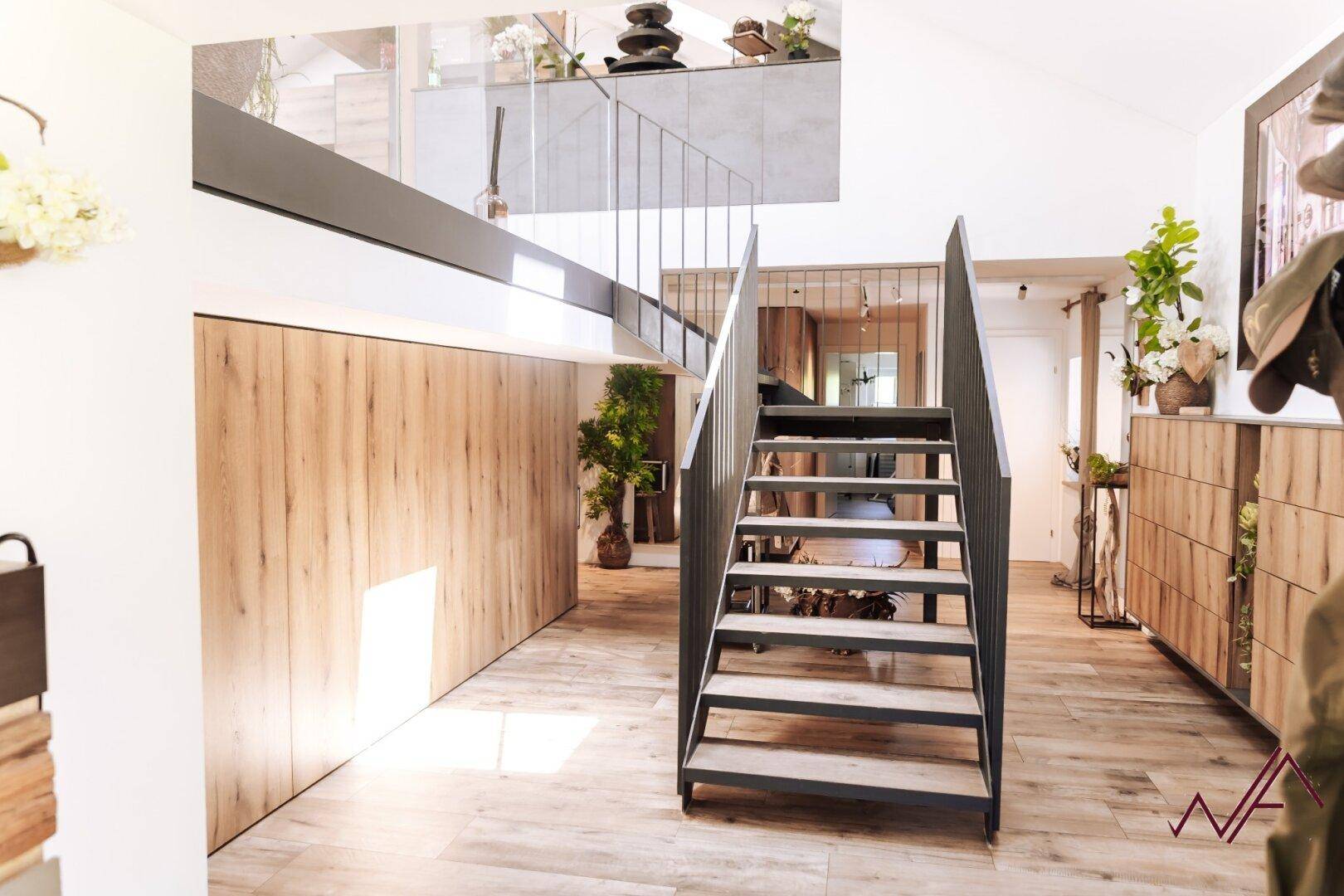 Heller Flur mit moderner Metalltreppe, Holzvertäfelung und offenem Blick auf die obere Etage.