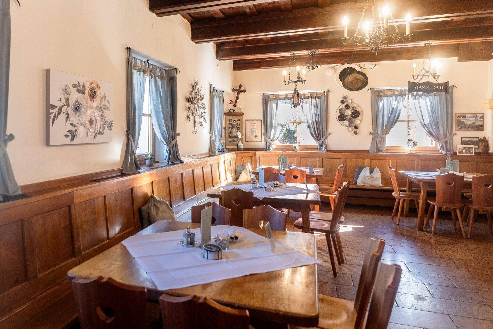 Heller Speisesaal mit Holztäfelung, traditionellen Vorhängen und rustikalen Holzmöbeln.