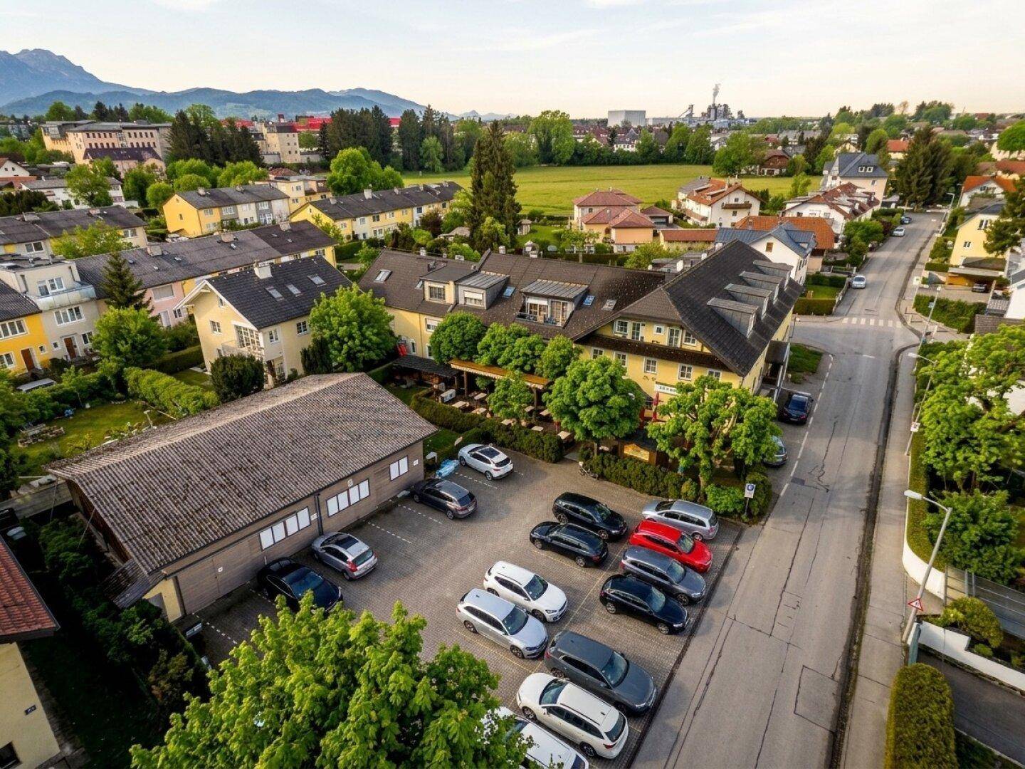 Luftaufnahme des Anwesens mit großem Parkplatz und angrenzender Straße in einer grünen Umgebung.