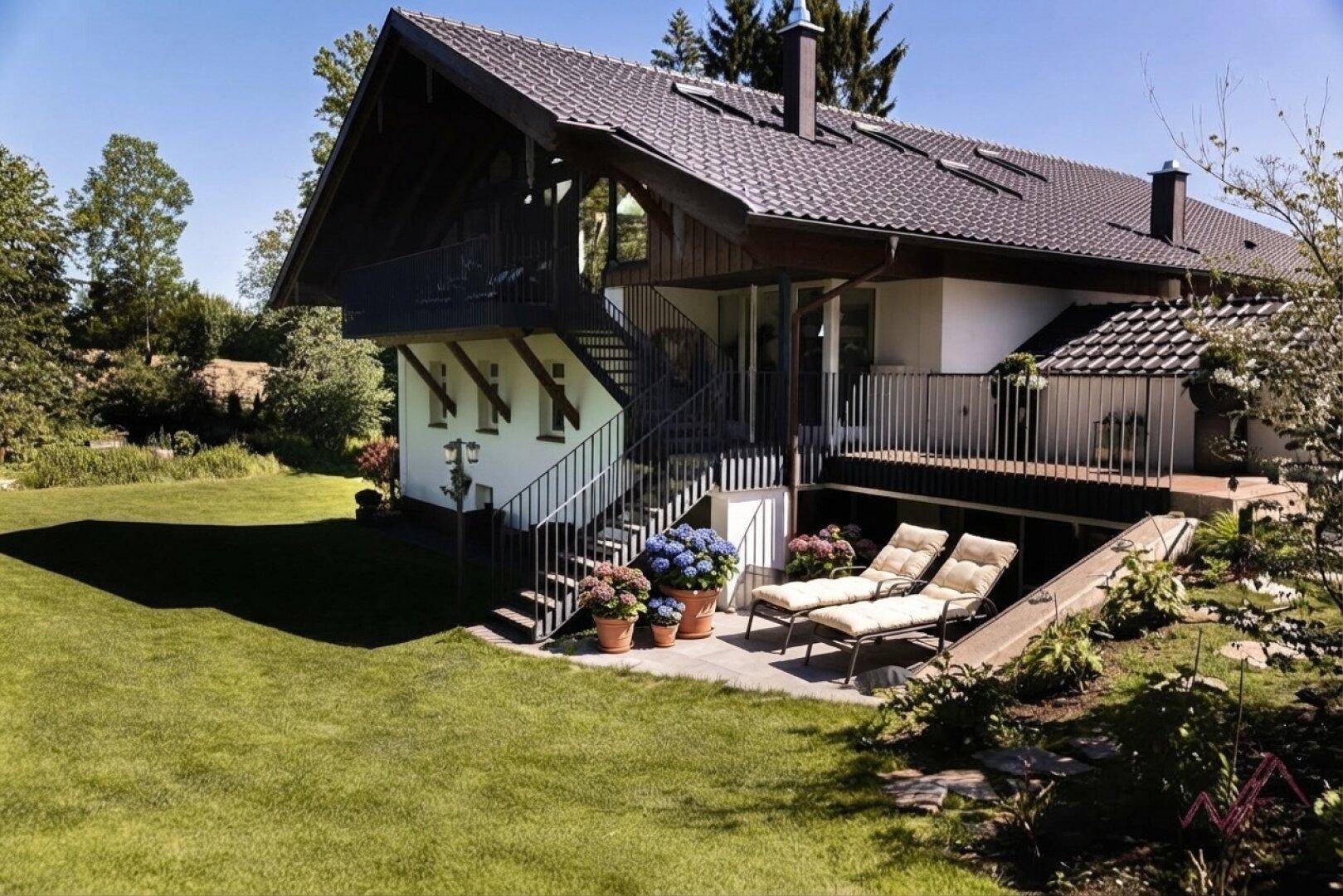 Gemütliche Terrasse mit Liegestühlen und Blumen, direkt am Haus mit Zugang zum Garten.