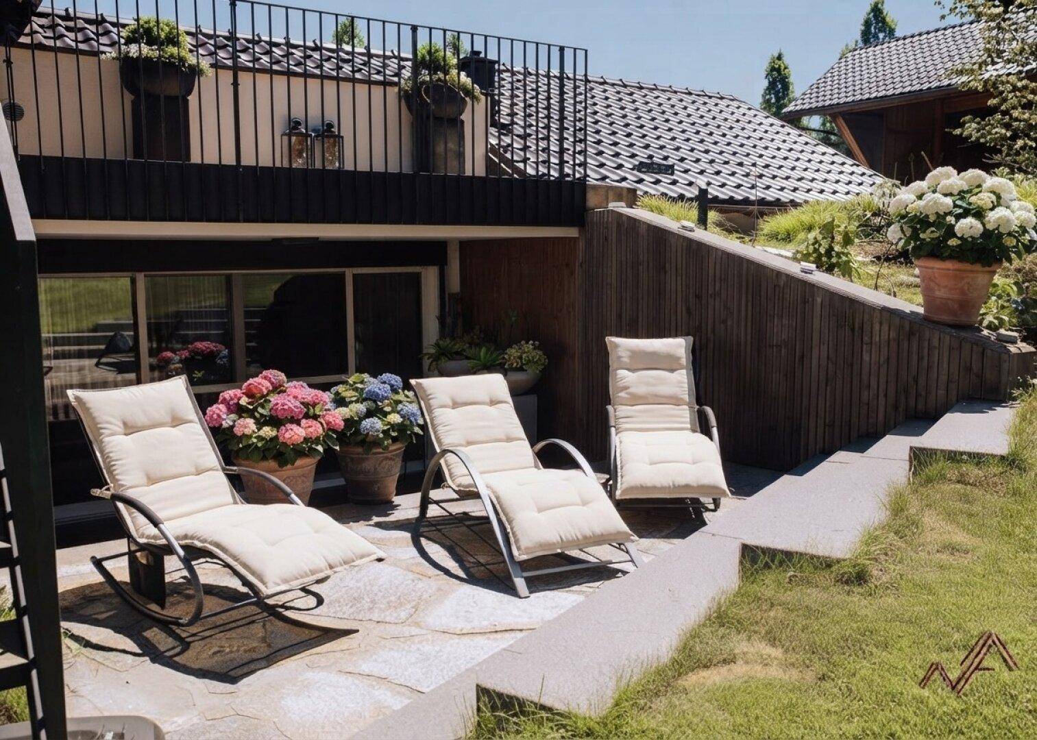 Gemütlicher Terrassenbereich mit Liegestühlen und Blumen, ideal zum Entspannen im Freien.