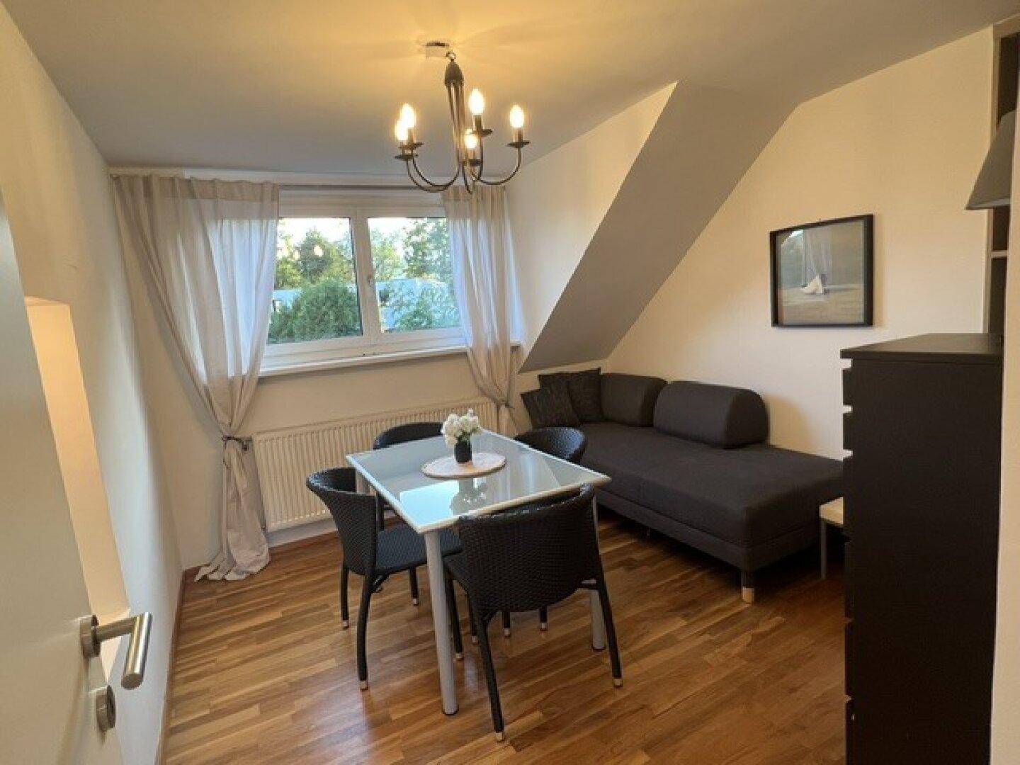 Heller Wohn- und Essbereich im Dachgeschoss mit Holzboden, Esstisch und gemütlichem Sofa.