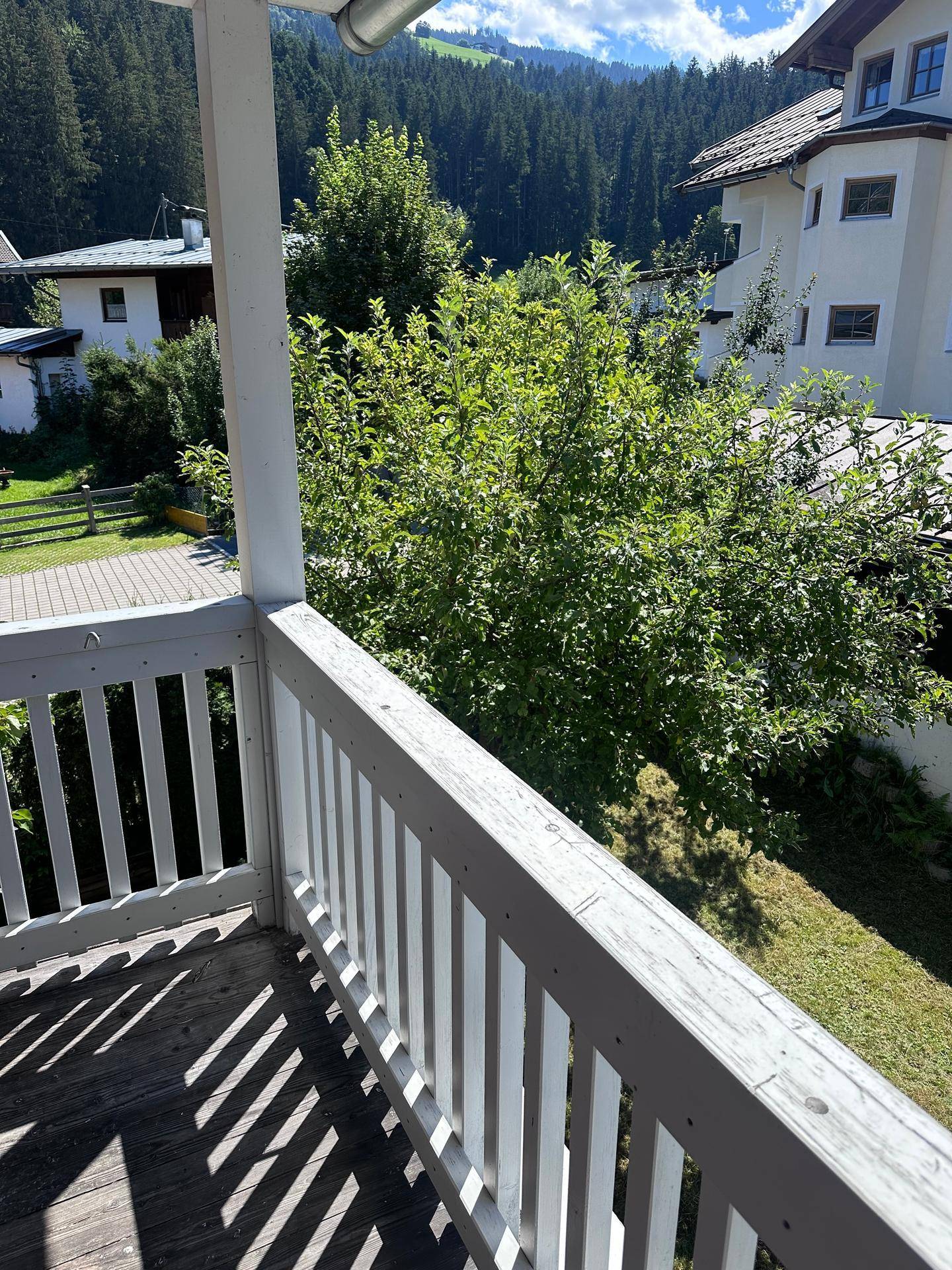 Balkon mit Holzbalkon und Blick auf die grüne Umgebung und die umliegenden Häuser.