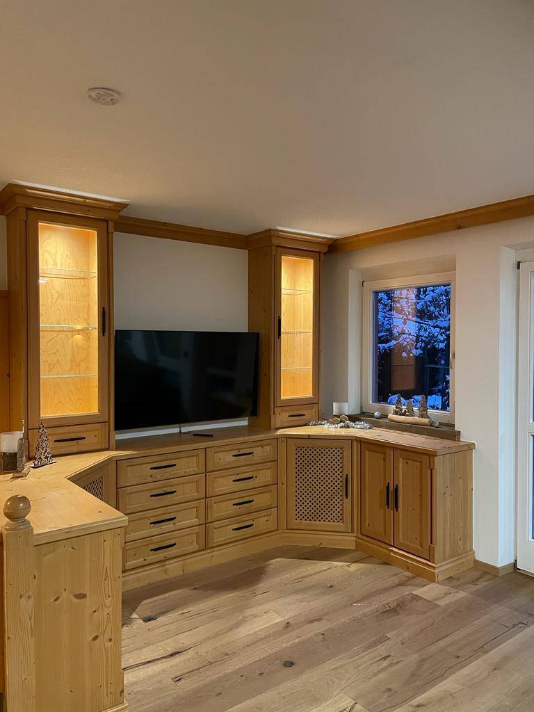 Maßgefertigte Holzmöbel mit integriertem Fernseher und Beleuchtung im Wohnbereich.