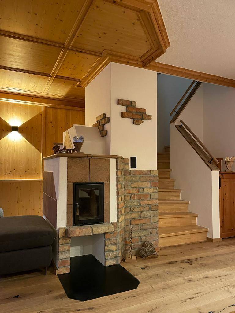 Heller Eingangsbereich mit Holztreppe und einem traditionellen Kamin aus Ziegelsteinen.