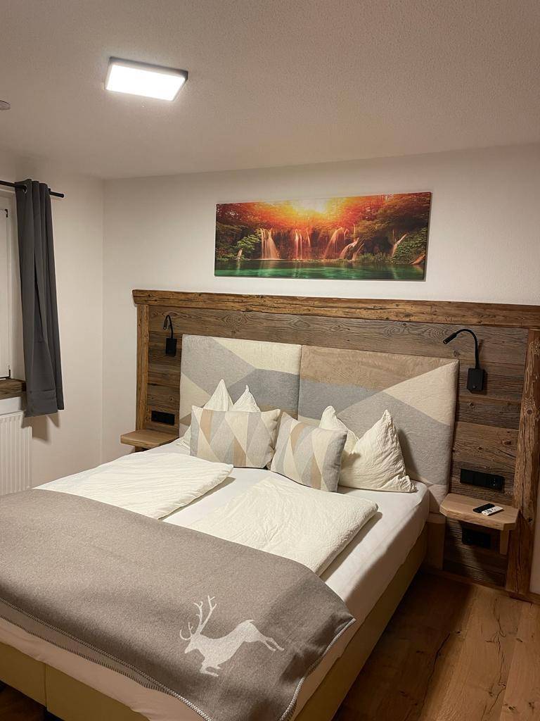 Komfortables Schlafzimmer mit Holzboden, gemütlichem Bett und einem farbenfrohen Landschaftsbild.
