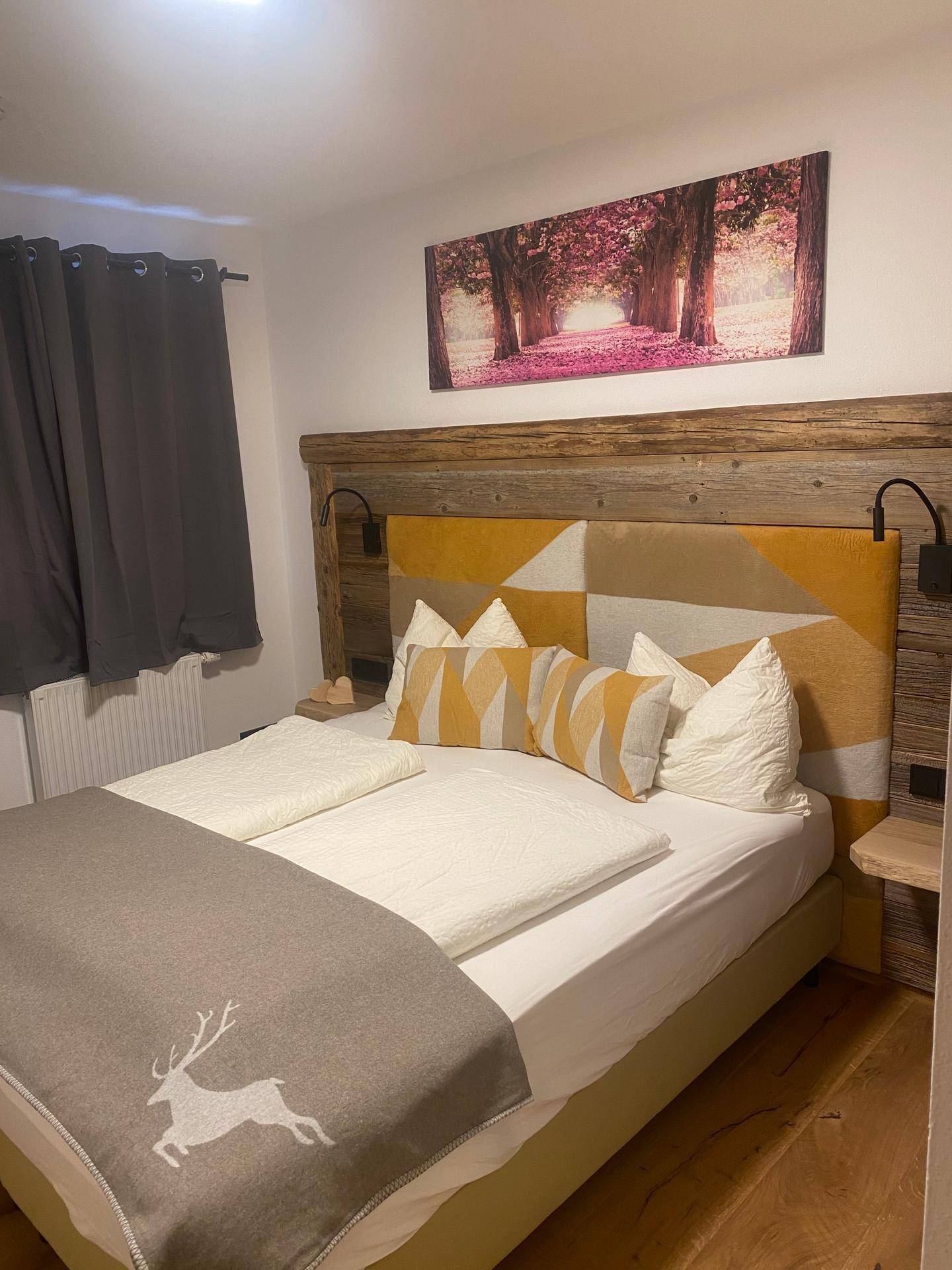 Freundliches Schlafzimmer mit Holzbett, gelben Akzenten und einem stimmungsvollen Wandbild.