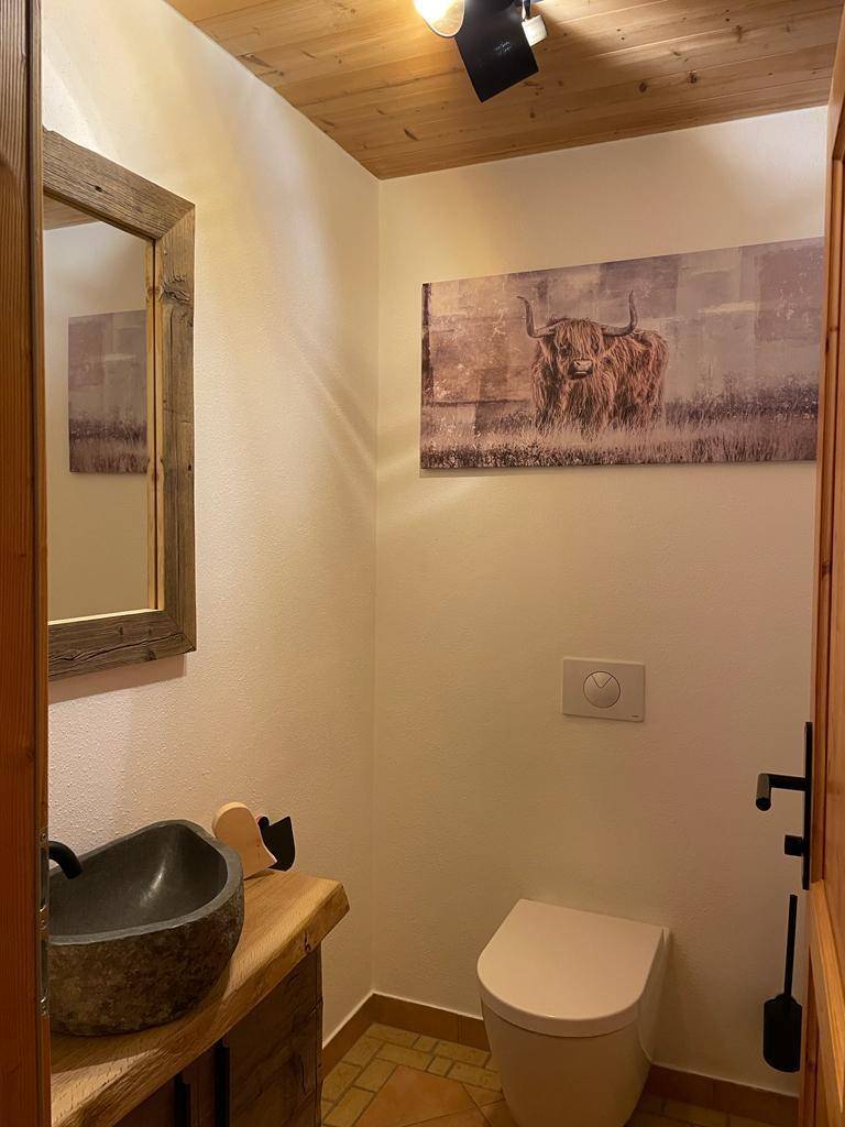 Rustikales Gäste-WC mit Steinswaschbecken, Holzwaschtisch und Terrakotta-Fliesenboden.