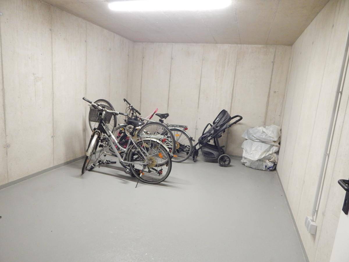 Geräumiger Fahrradraum im Untergeschoss mit Betonwänden und Abstellmöglichkeiten für Fahrräder.