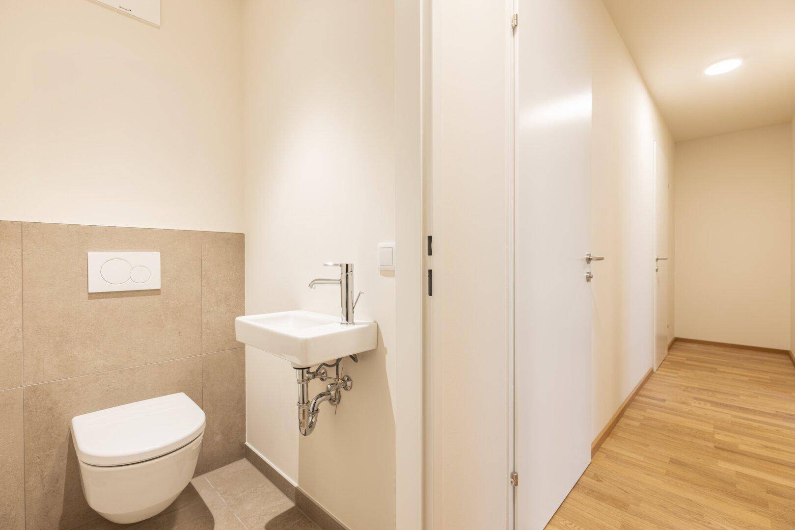 Kleines Gäste-WC mit wandhängender Toilette und kompaktem Waschbecken.