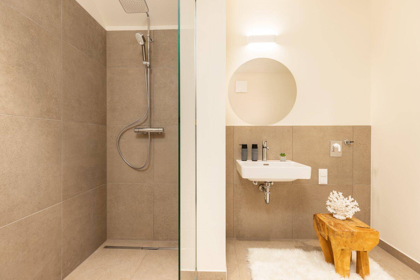 Detailansicht des modernen Badezimmers mit begehbarer Dusche und elegantem Waschbecken.